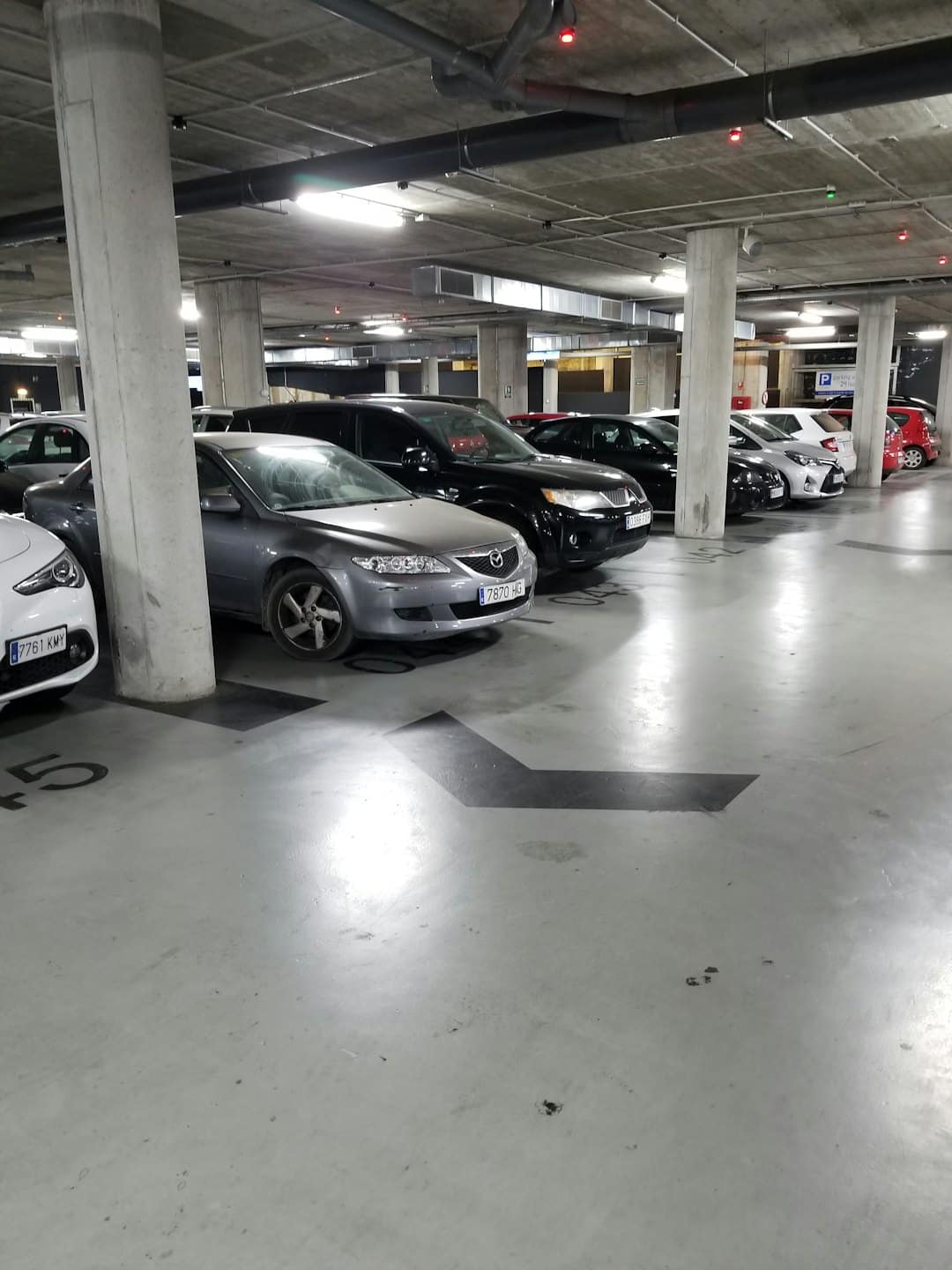 Beton yeraltı otoparkında sıralar halinde park edilmiş arabalar.